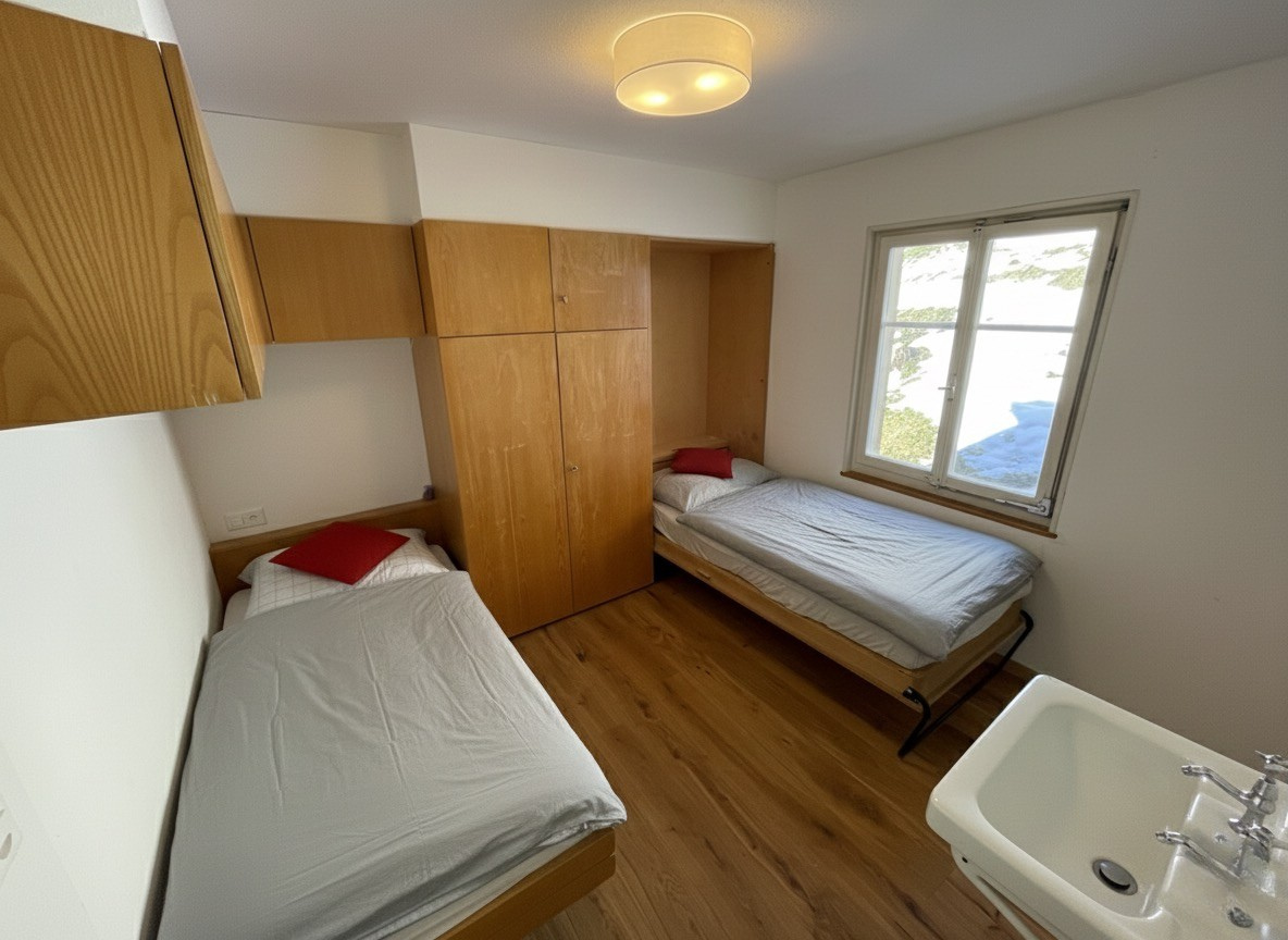 Helles Schlafzimmer mit zwei Einzelbetten und Blick in den Schnee